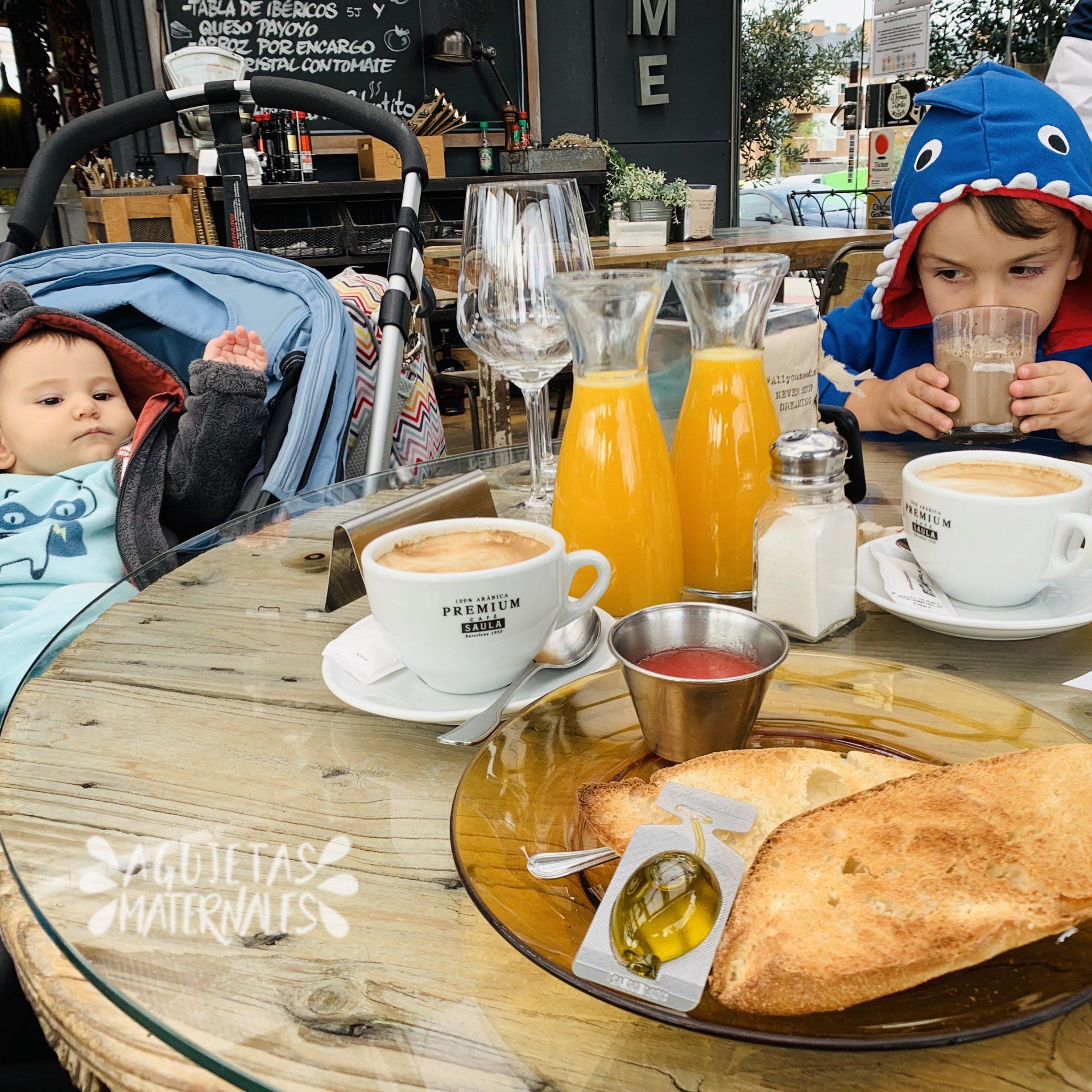 niño de dos años y un bebé en una mesa con desayuno