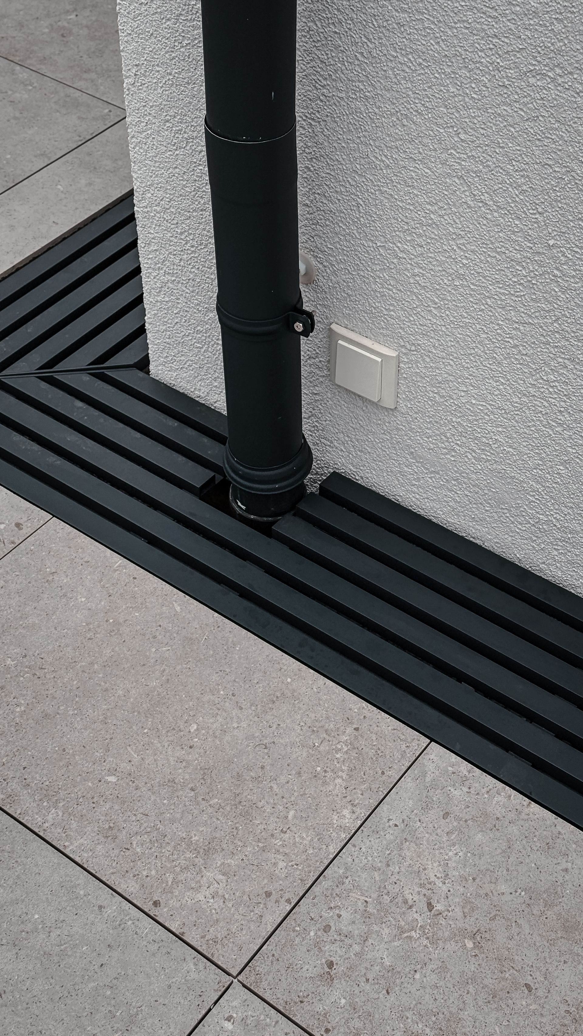 Maßgefertigtes Gitterrostsystem für ein modernes Fertighaus mit individuellen Ausschnitten für Fenster, Fassadenanschlüsse und Fallrohre. Verlegefertige Aluminium-Gitterroste mit passgenauer Konstruktion für Terrasse und Hauseingang.
