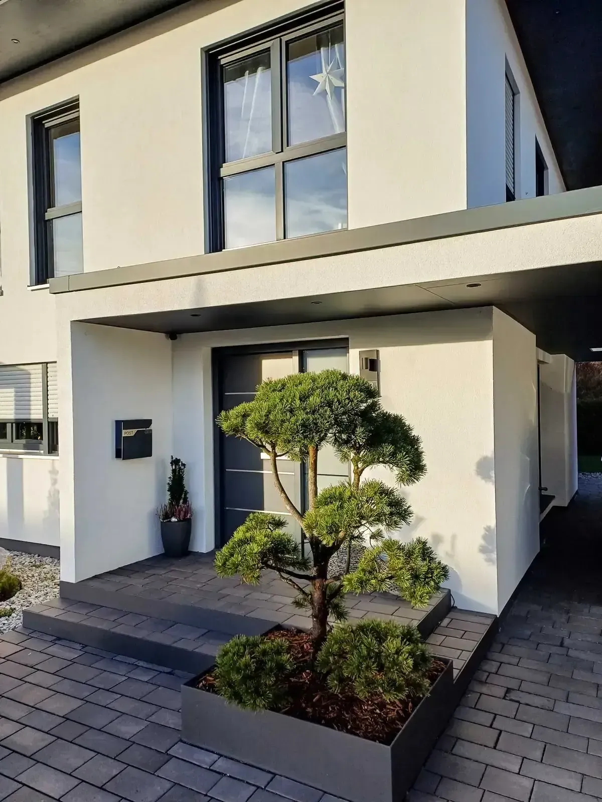 Eingangspodest eines Fertighauses mit einem Beet