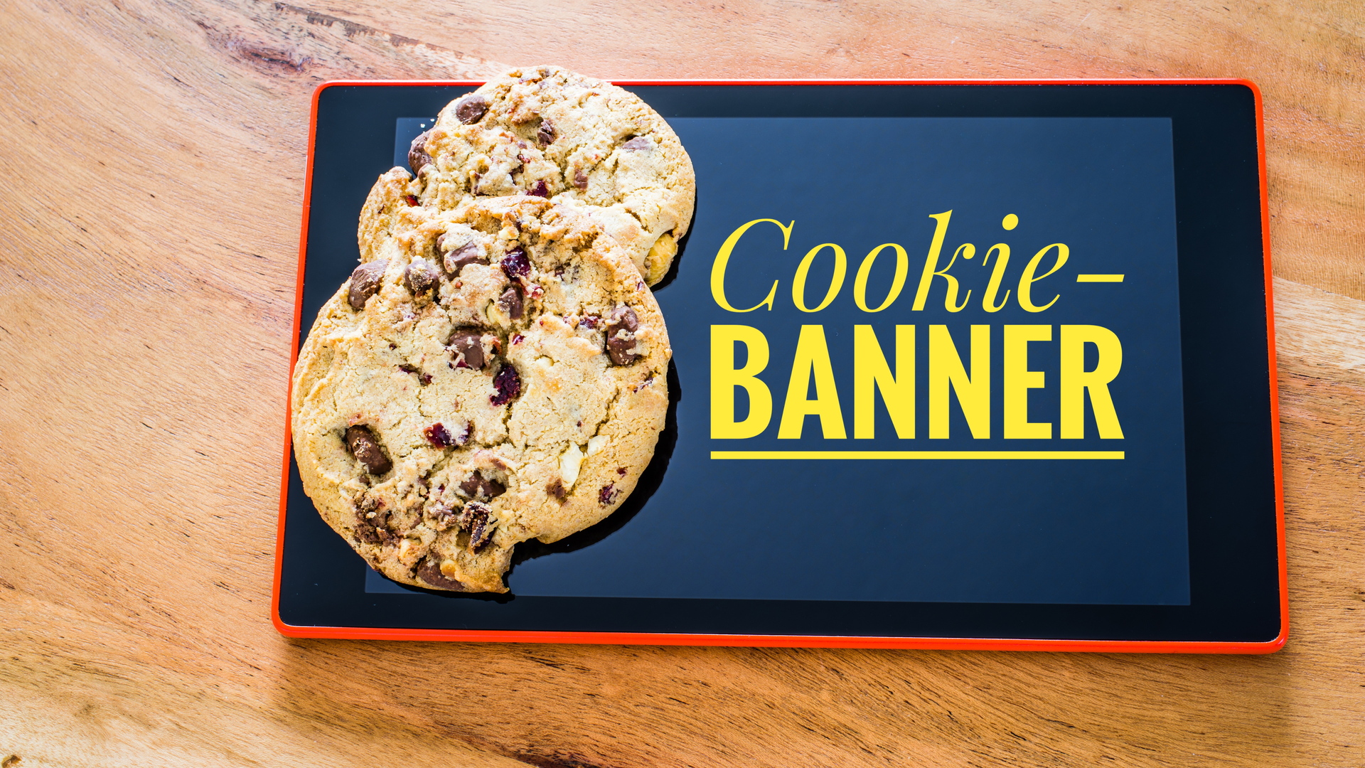 Das Bild zeigt ein Tablet auf einem Holztisch mit dem gelben Schriftzug Cookie-Banner und zwei auf dem Tablet liegende Kekse (im Englischen: Cookies).
