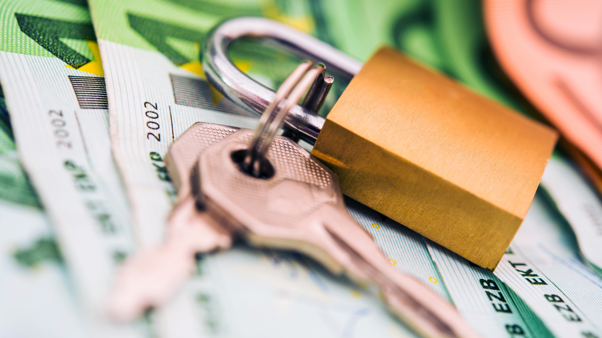 Das Bild zeigt einen Vorhängeschloss mit einem Schlüssel, der auf einer Vielzahl von Euro-Banknoten liegt. Dieses Bild kann symbolisch für finanzielle Sicherheit und Schutz stehen, insbesondere im Kontext von Finanzen wie einer Mietkaution, bei der Geld sicher hinterlegt wird, um als Sicherheit zu dienen. Die Darstellung des Schlosses auf dem Geld könnte auch auf die Notwendigkeit hinweisen, Investitionen oder Einsparungen zu sichern, was in vielen Bereichen wie dem Bankwesen oder der Immobilienverwaltung relevant ist.