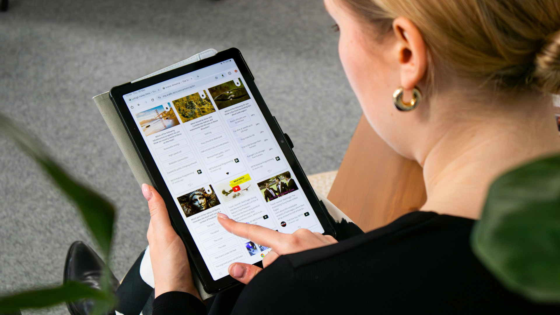 Eine Frau betrachtet auf einem Tablet verschiedene Online-Karten oder Info-Kacheln. Die Perspektive zeigt ihren Finger, der über den Touchscreen fährt – Symbol für digitales Leben und Informationszugang.