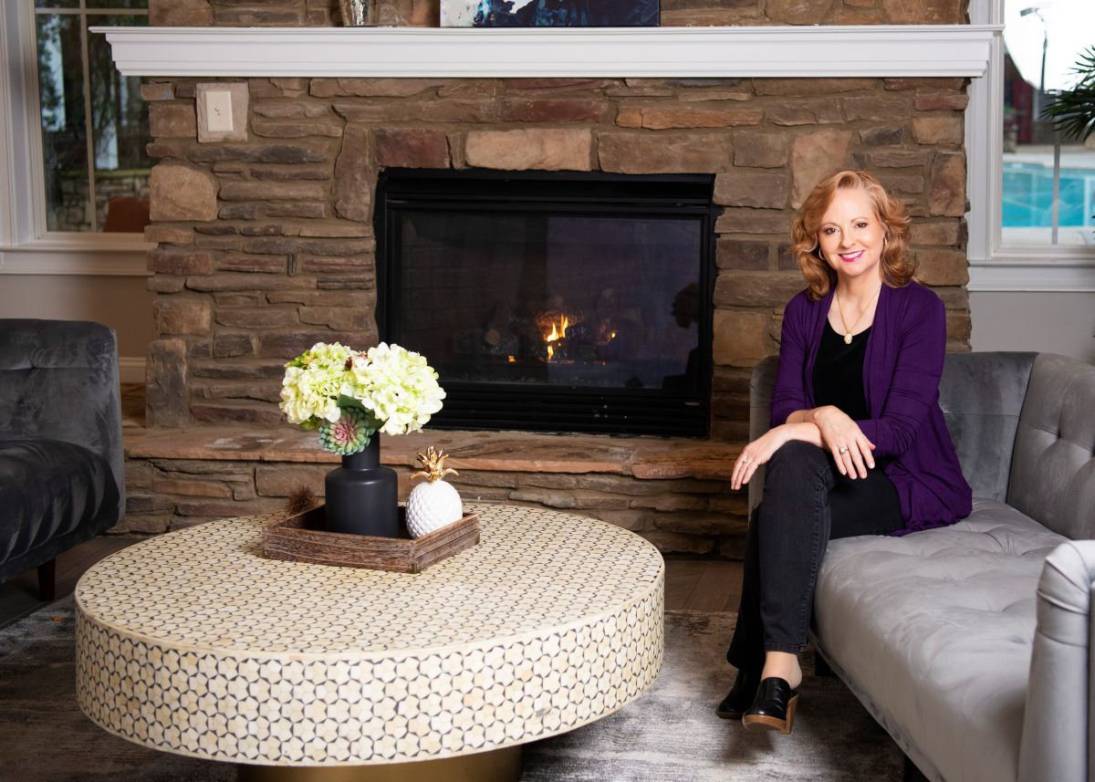 Gina M. Longo in a room with a fireplace.