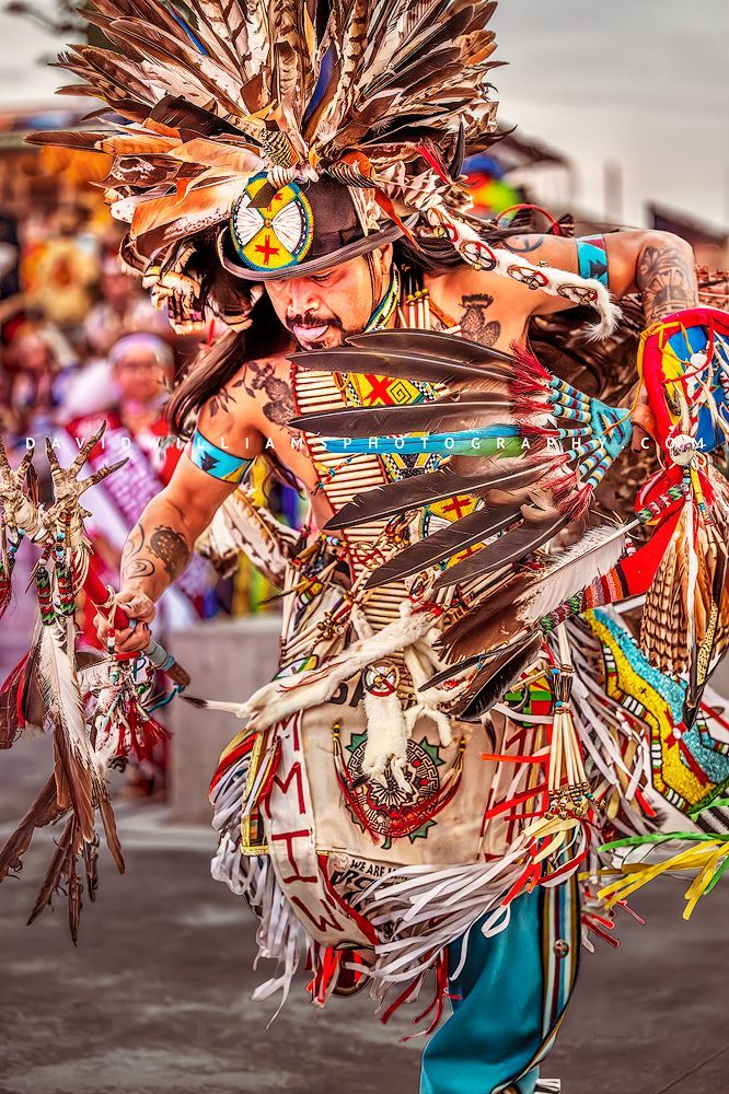 Close-up of a Hopi Indian in vibrant ornate regalia performing a traditional war dance, captured as a vertical fine art storytelling portrait.