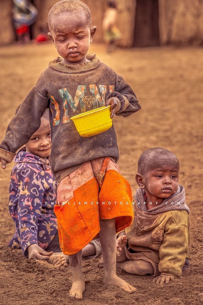 3 Maasai boys in worn out clothing eating a meal, Kenya, Africa