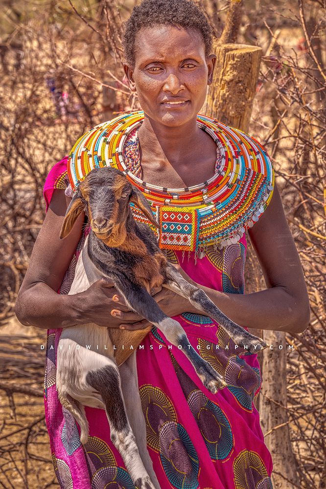 A beautiful Maasai woman with a goat in her arms, Kenya