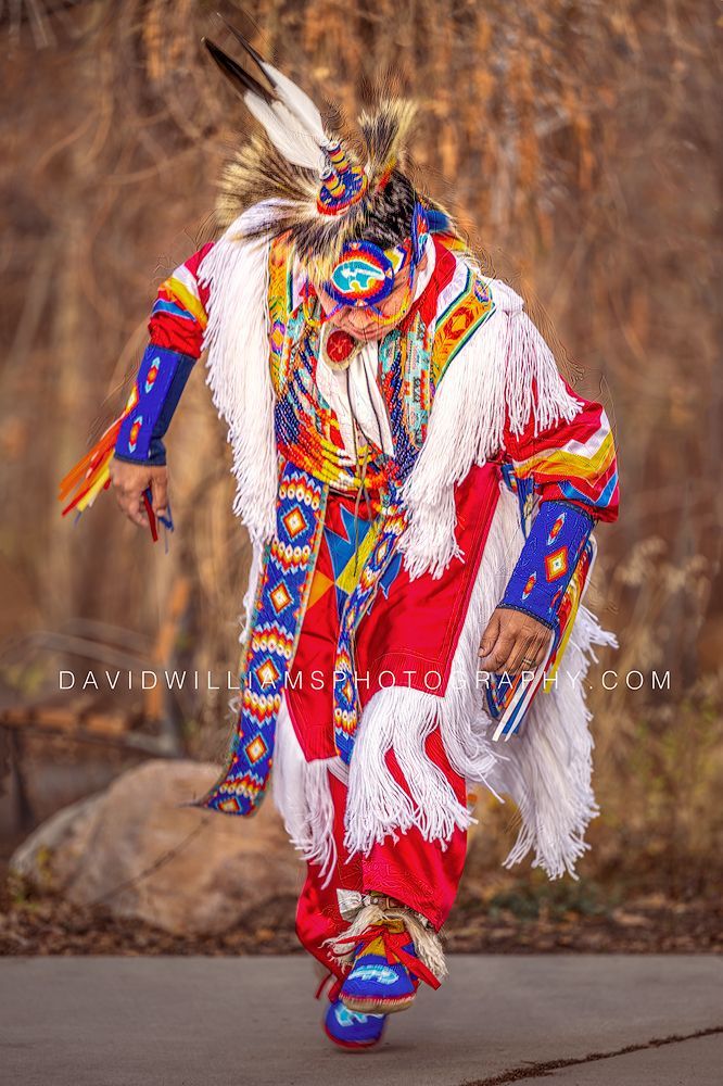 Vertical portrait of a Native American man performing the Grass Dance in full regalia in Salt Lake City, Utah.
