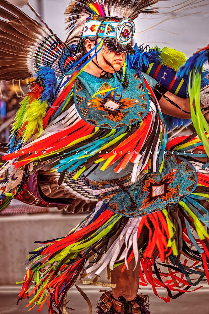 A brightly dressed Navajo Indian performing a traditional War Dance in full regalia, captured vertically as a fine art storytelling portrait.