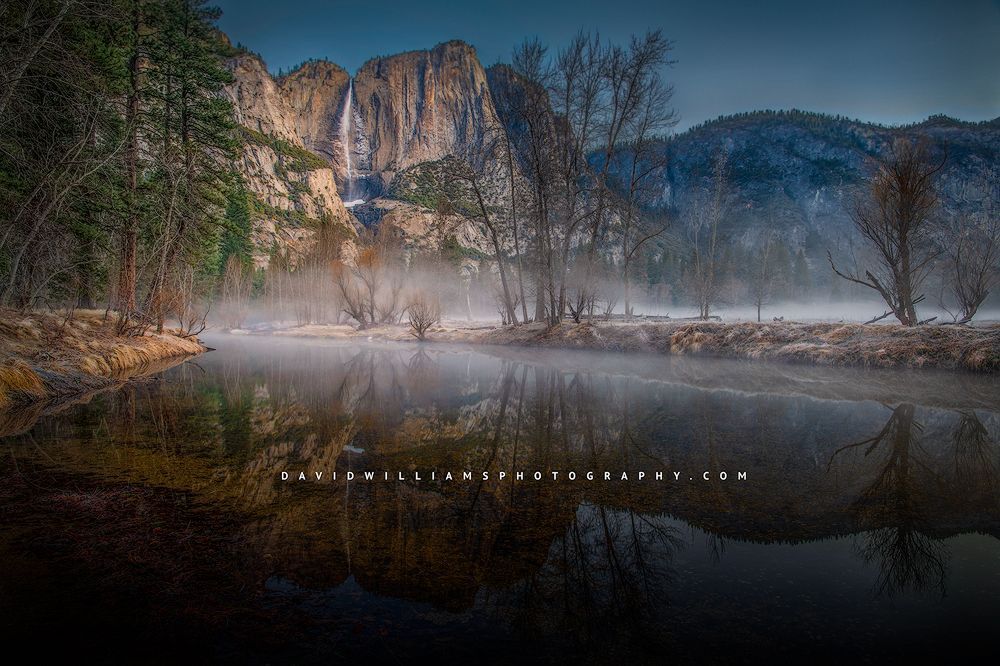 The fog rolls in on a crisp and clear Winter morning overlooking the river from Swinging Bridge at Yosemite National Park, California