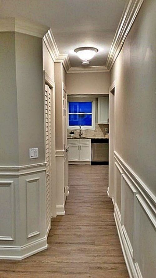Applied molding on lower walls and crown molding at the ceiling in a hallway by The Renovation Company