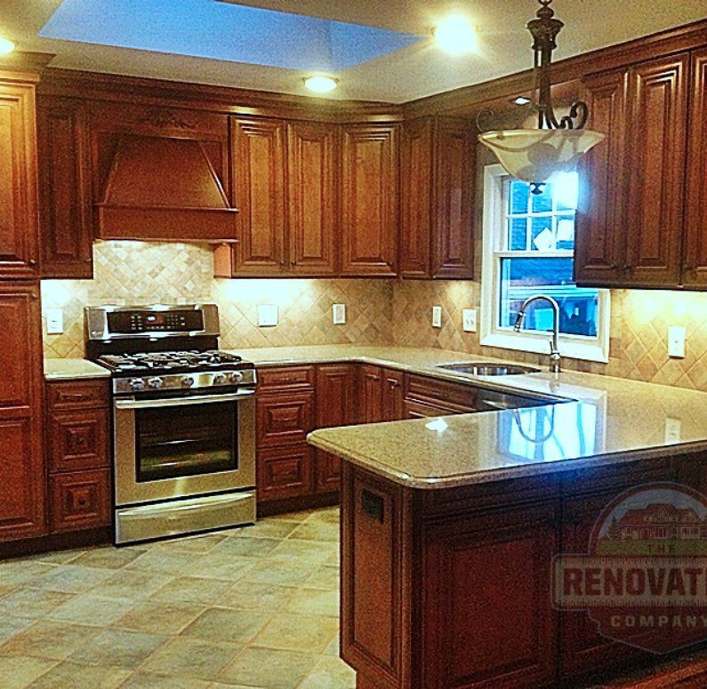 Renovated kitchen by The Renovation Company with dark cabinets, granite counters and a tiled backsplash.