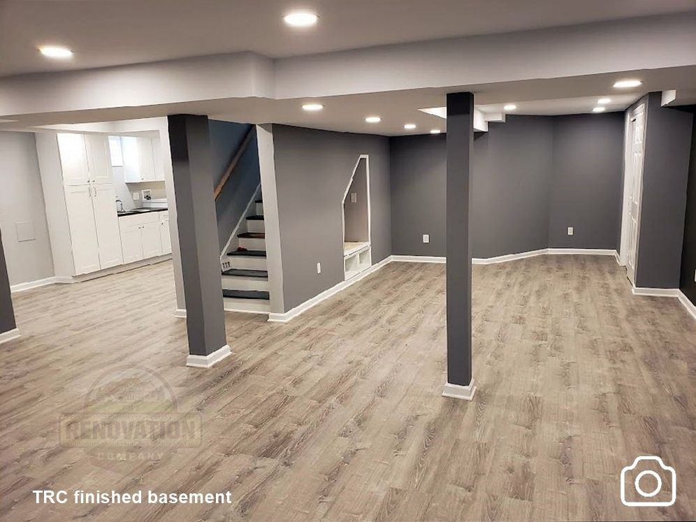 Basement finished by The Renovation Company with LVT flooring, dark gray walls, white trim, and recessed LED lighitng
