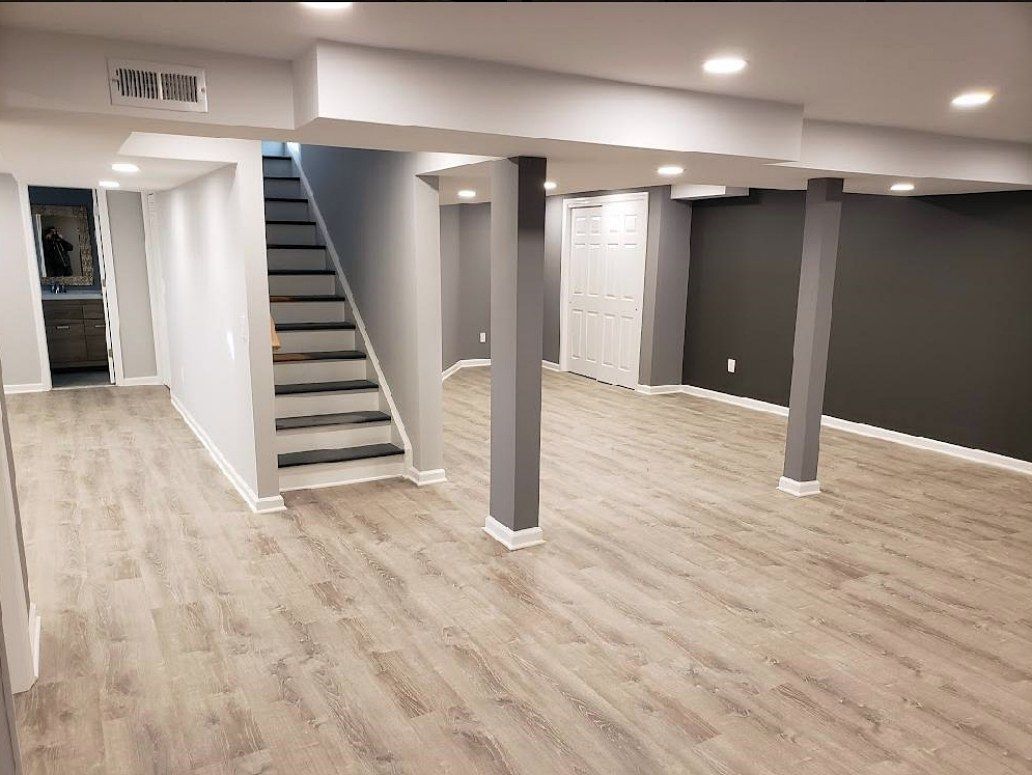 Finished basement by The Renovation Company with LVT flooring, gray accent walls, white trim, and recessed lights.