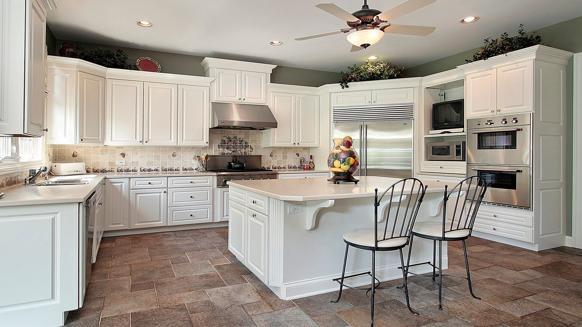 A beautiful white kitchen with a center island, granite counters, and a unique backsplash tile design