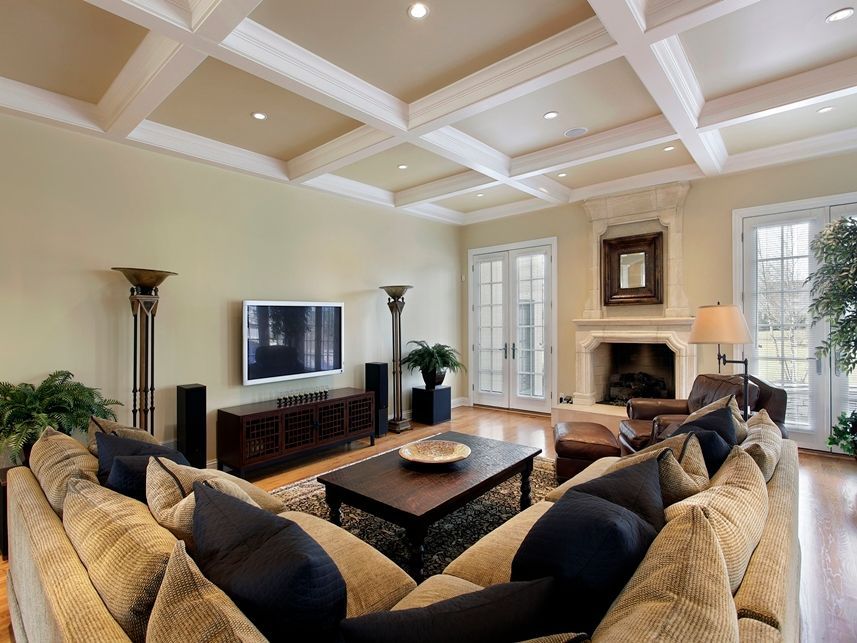 Stock photo of a furnished living room with sofa, coffee table, tv, fireplace, and a coffered ceiling