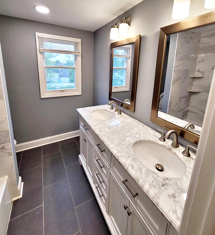 bathroom renovation by The Renovation Company with a double basin vanity with a white marble top and brushed nickel faucets