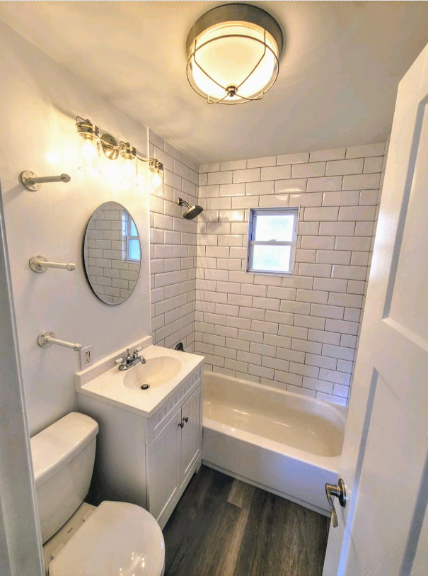 Bathroom renovation by The Renovation Company with white subway tile on the tub walls,and a new floor and door.