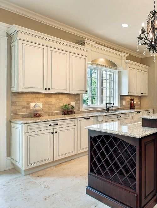 An upscale kitchen with white cabinets and dark colored island cabinets