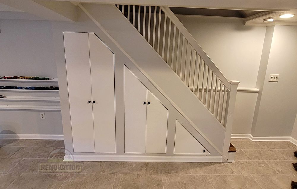 Under staircase storage solution in a finished basement with angled doors installed by The Renovation Company