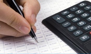 closeup of a hand holding a pen with a visible calculator nearby