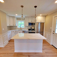 Renovated kitchen by The Renovation Company with white cabinets and quartz counters