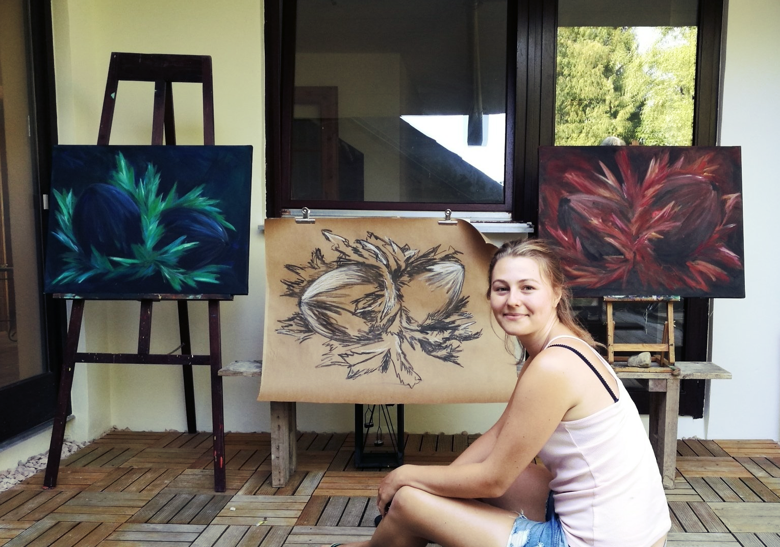 Sophia de Conjoul sitzt vor ihren Kunstwerken