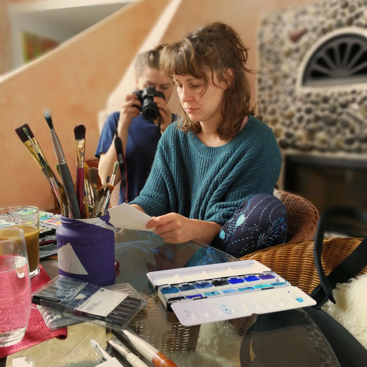 Rachel Alisa sitzt an einem Tisch und malt an einem Kunstwerk