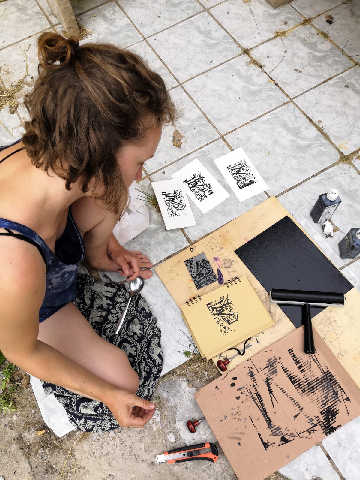 Rachel Alisa Rachel Alisa sitzt auf dem Boden und arbeitet an einem Linoldruck