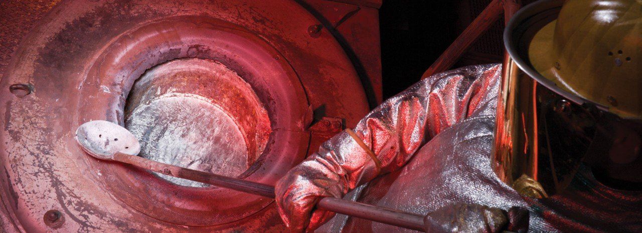 Nella fonderia di magnesio un operatore toglie alcune impurità del metallo dal forno di contenimento
