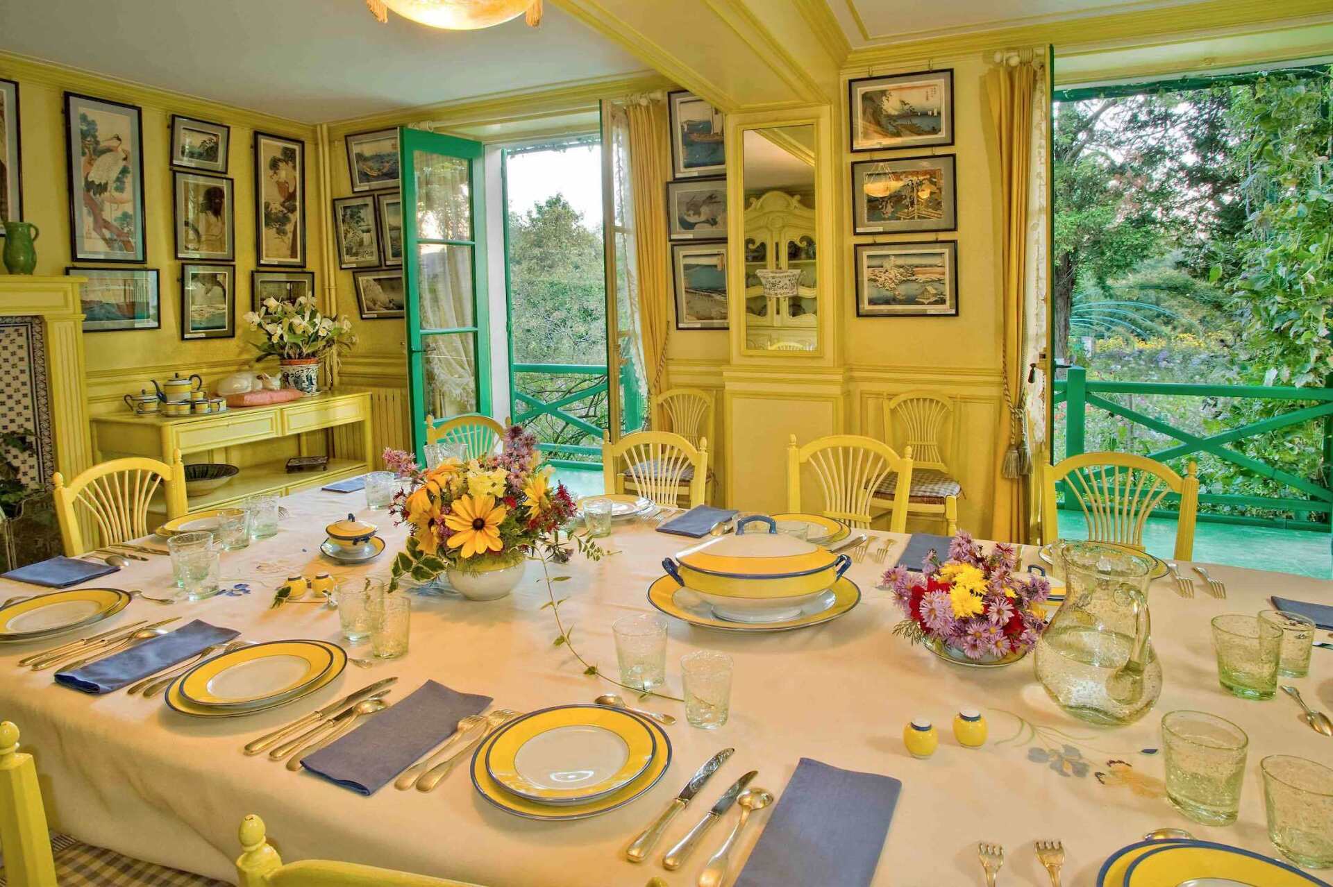 On the ground floor, the visitor enters the inviting dining room, decorated in two shades of yellow. The kitchen, covered in Rouen-blue tiles, was the hub of the house; the meals served in the artist's home were exceptional and did not tolerate slackness.  Dinning room - Maison et jardins de Claude Monet Giverny