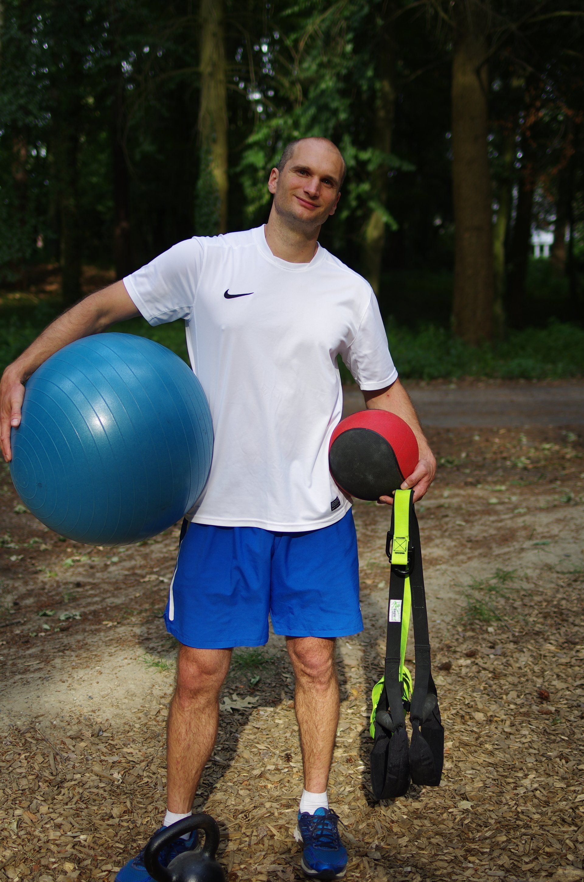Personal Training Berlin, Potsdam, Oberhavel mit Trainer Benjamin Müske, der gerade eine Stabilisationsübung auf einem Medizinball, Pezziball und einem Kettlebell durchführt und dabei fröhlich in die Kamera lacht