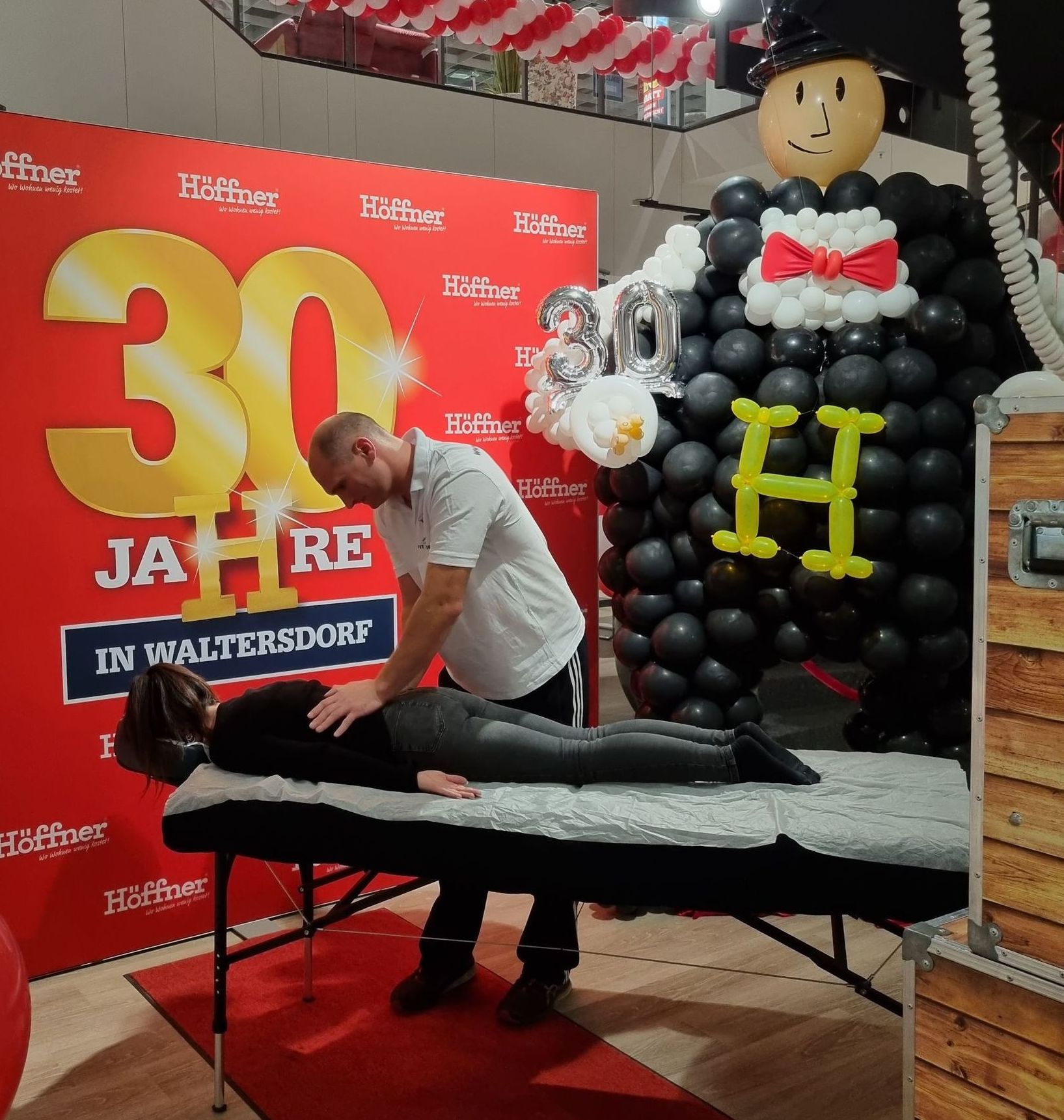 Müske massiert eine Frau auf einer Massageliege anlässlich des 30-jährigen Höffner-Jubiläums in Waltersdorf