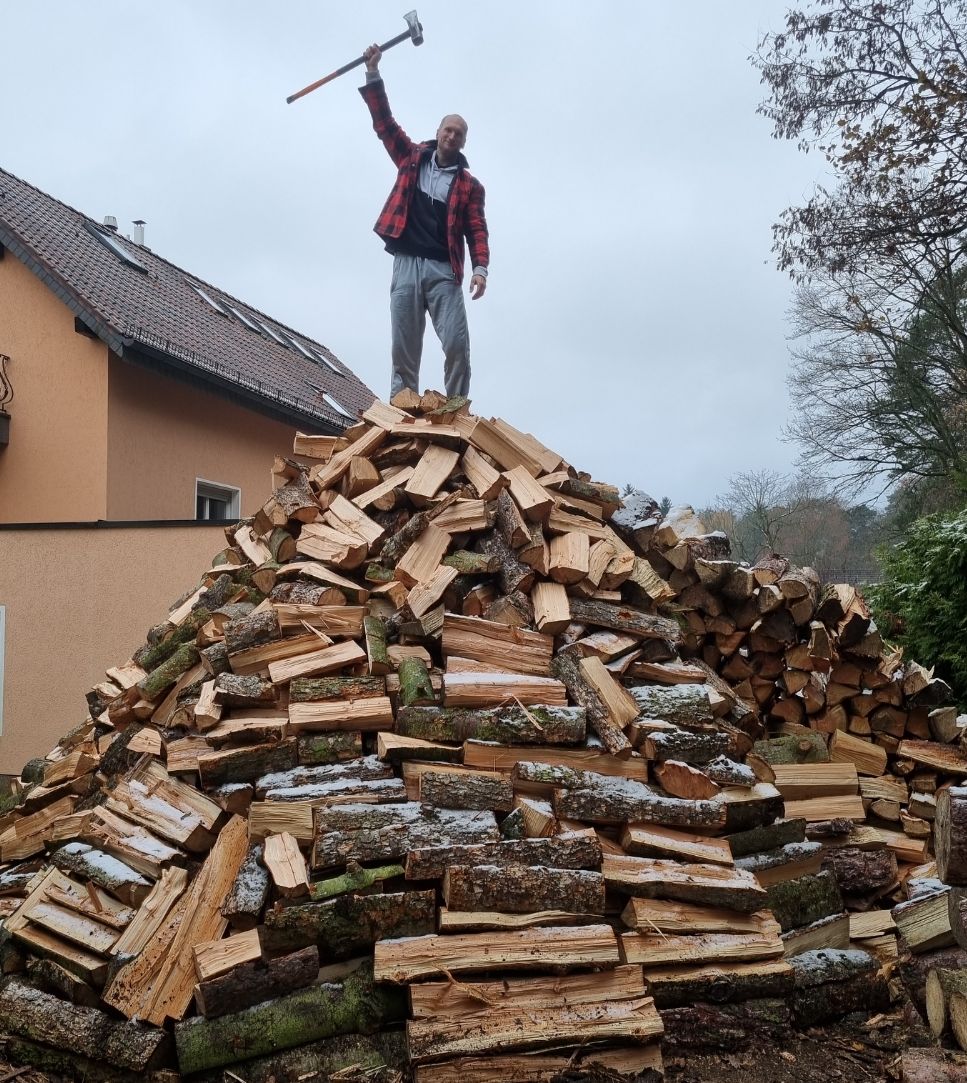 Personal Trainer Benjamin Müske steht auf einen riesig, selbstgehackten Holzberg in Berlin