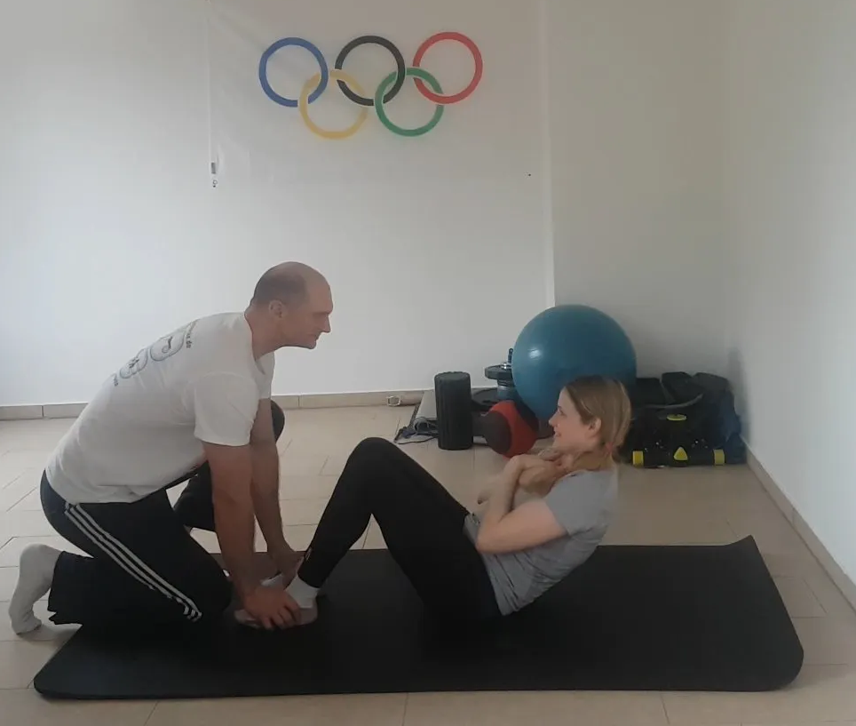 Das Bild zeigt ein Personal Training in Berlin, bei dem Trainer Benjamin Müske mit einer Kundin eine Bauchmuskelübung durchführt.