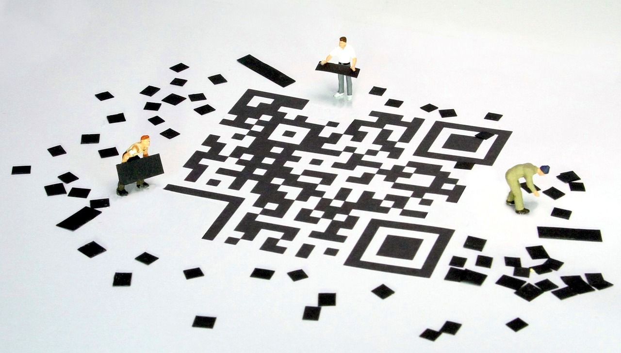 Zwei kleine menschliche Figuren, die versuchen einen zerbrochenen QR-Code wieder zusammenzusetzen.
