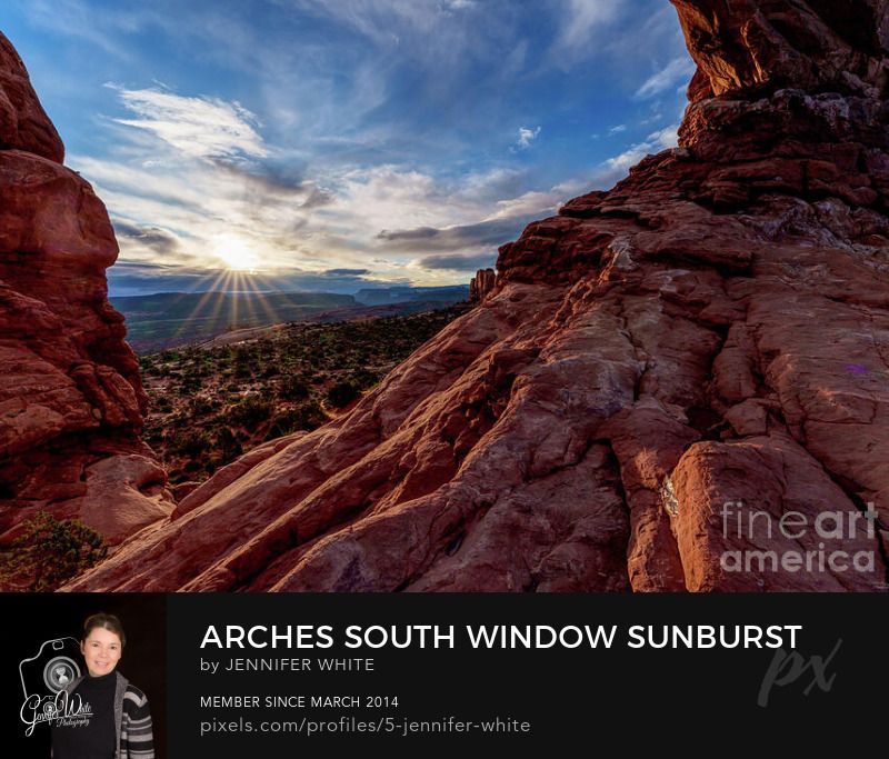 A sun bursts of rays over some morning clouds during sunrise while I was standing underneath the South Window rock formation at the Windows Section in Arches National Park in Moab, Utah, United States. You can see some cook rock formations and mountains in the distance. It was so beautiful. I captured different angles of it as I climbed around on the steep rocky incline of the arch.