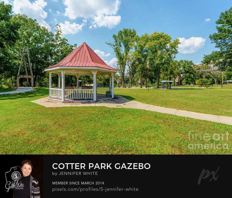 A gazebo at Big Spring Park in Cotter, Arkansas, United States on a beautiful summer afternoon. Behind it, there is an interesting art structure made of concrete and railroad steel and it stands over a sidewalk for you to walk through. In the distance you can see some of the historic concrete arched Cotter Bridge. This is also part of the Ozarks and there is a natural spring at the park.