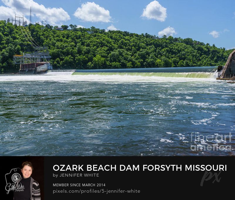 A powerful cascade of water flows over the historic Powersite Dam on the White River in Forsyth, Missouri, USA. Surrounded by the beauty of the Ozarks, this dam, constructed in 1911 as Missouri’s first hydroelectric dam, creates the Lake Taneycomo reservoir and remains an important landmark. Known locally as the Ozark Beach Dam, it combines history with striking scenery. The rushing waters shimmer beneath a bright blue sky with scattered clouds, while lush green trees frame the riverbanks. The force of the falls stirs bubbles across the surface, adding energy and motion to this timeless Ozark waterscape located just east of Branson, Missouri.