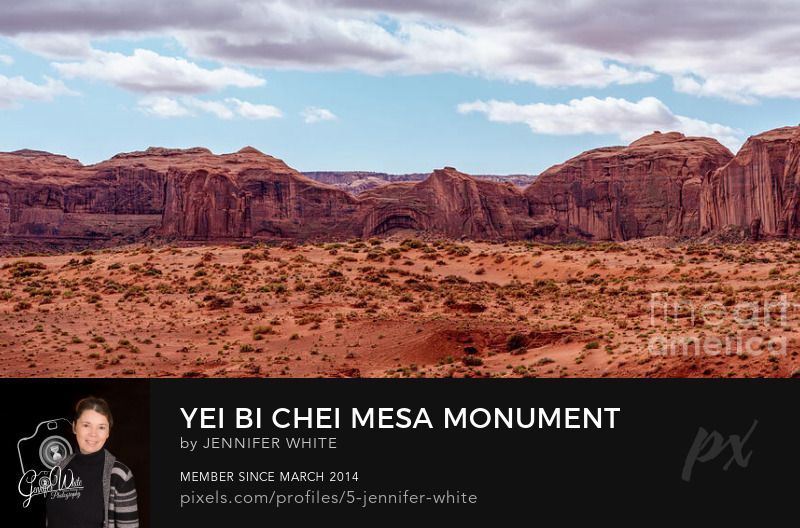 This panorama photograph captures a view of one of the mesa rock mountains in Monument Valley, Arizona. This is part of the Yei Bi Chei and Totem Pole area. Clouds are drifting into the area as a storm was forming behind me. Some alcove cave like formations can be seen. This is part of the Navajo Tribal Park. The red sand contrasts with the blue sky. The clouds have a hint of purple to them. I captured this from the Sand Spring area.