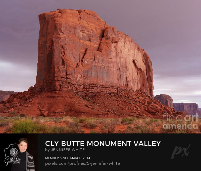 A close view of the towering Cly Butte in Monument Valley as a storm rolls in over the southwest desert landscape. Part of the Navajo Tribal Park, it stands at an elevation of 5,820-foot-elevation at the summit in Navajo County, Arizona, USA. The name refers to a Navajo chief named Cly who is buried at the base of this butte. The storm clouds have a pink and purple cast adding drama to the already bold and majestic scene.