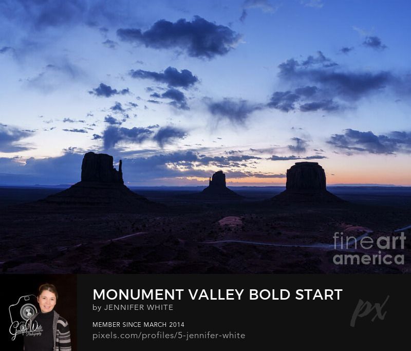 Click to see photo A bold but peaceful morning with dramatic clouds start the day over Monument Valley during the blue hour just before sunrise. The unmistakable silhouettes of the East Mitten Butte, West Mitten Butte, and Merrick Butte stand as silhouettes against a dawn sky.
