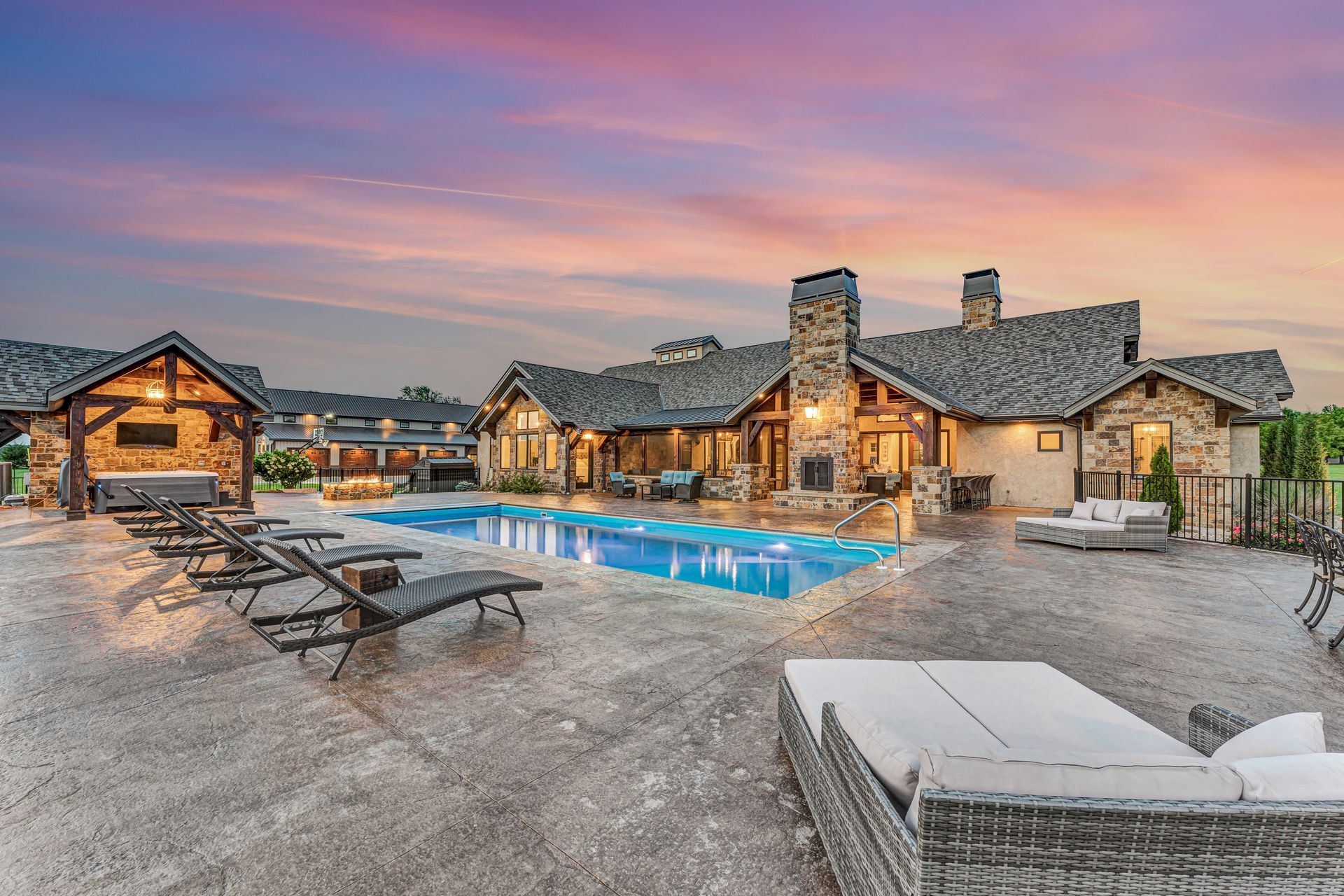 A dusk twilight exterior back patio with pool of a luxury home in Rogersville, Missouri. Professional photo by Jennifer White Timeless Moments Photography. Home built by Old World Cottages near Springfield Missouri.