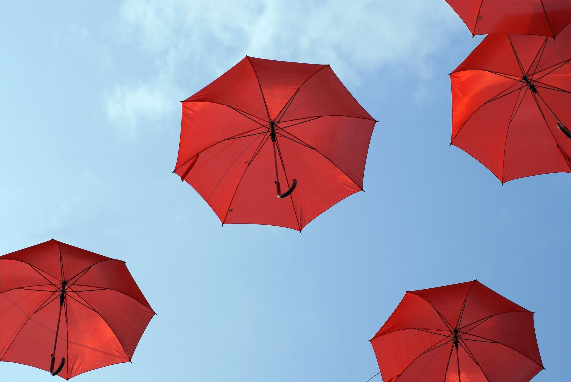 Mehrere fliegende rote Regenschirme am Himmel mit dem Button