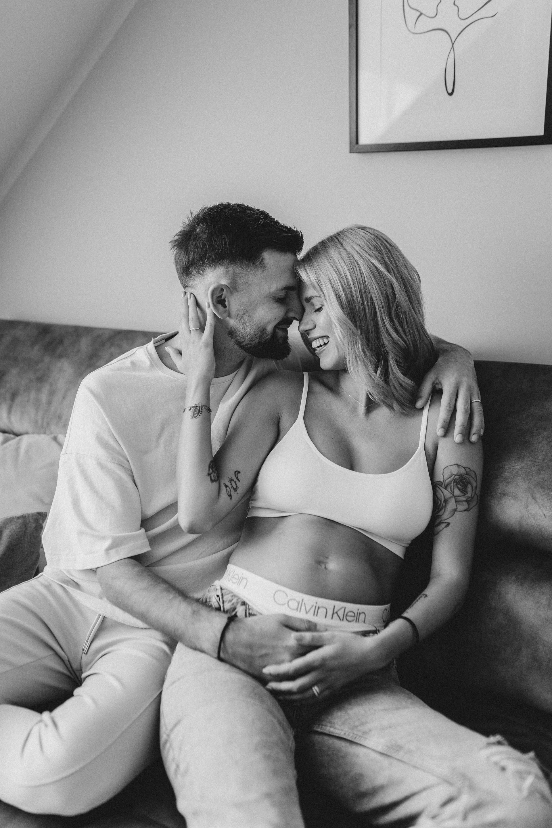 schwangerschaft babybauchshooting werdende eltern auf sofa homeshooting