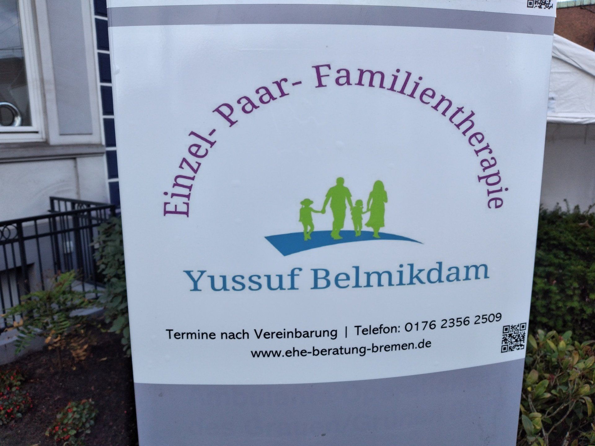 Außenschild der Praxis Einzel- Paar- und Familientherapie Yussuf Belmikdam Logo Eltern und zwei Kinder