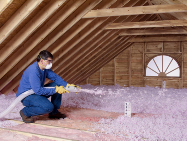 Insulator spraying blown-in insulation into an attic