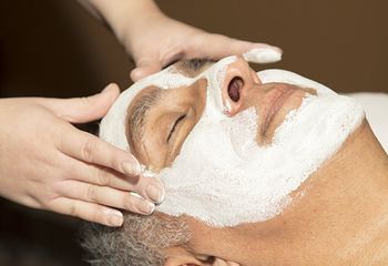 Hands applying a skin care mask to a man's face