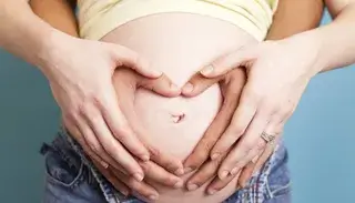 Man and woman holding hands on pregnant stomach
