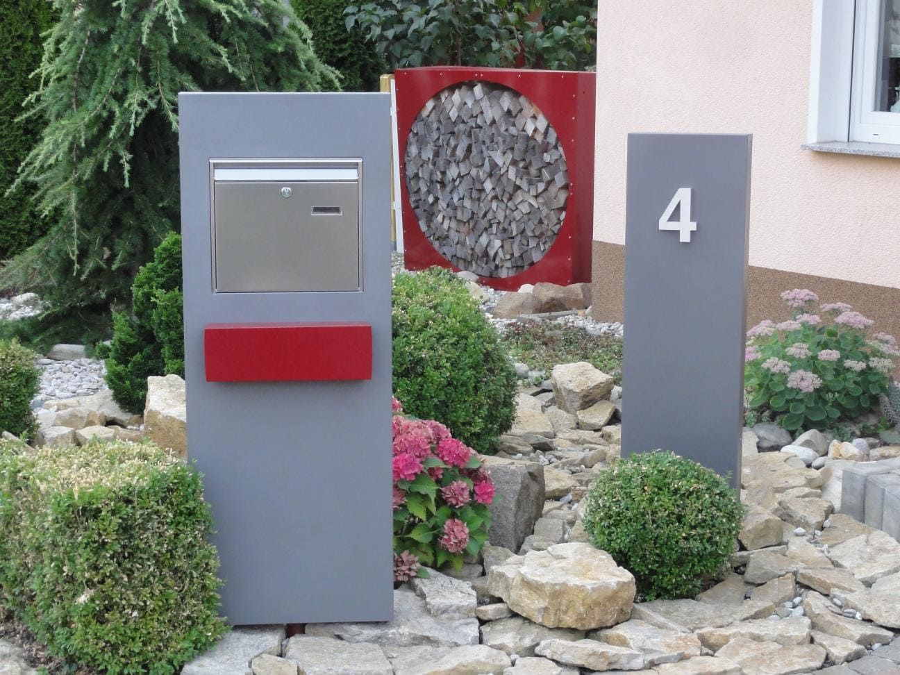 Gartenstele aus Metall als Briefkastenanlage in einem modernen Vorgarten