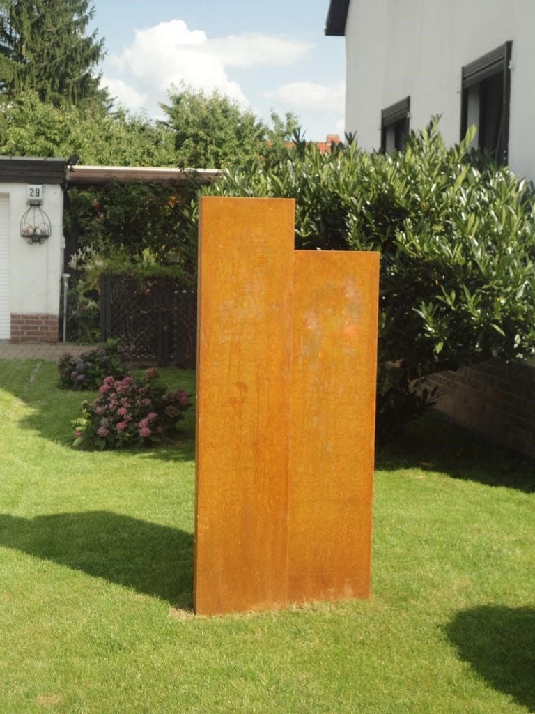 Gartenstelen aus Cortenstahl stehen als Dekoration im Garten auf einer Wiese